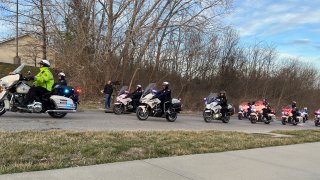 More than a dozen officers line up to escort the bodies of an Independence, Mo., police officer and a Jackson County court worker to the medical examiner's office